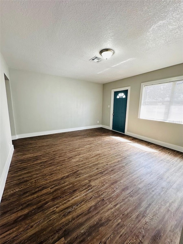 interior space with dark wood-style floors, visible vents, and baseboards