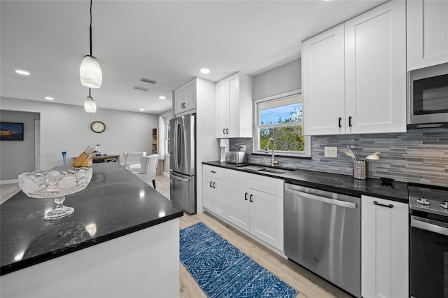 691 Gulf Bay Rd, Longboat Key, FL 34228 - kitchen featuring stainless steel appliances, a sink, backsplash, white cabinets, and light wood-style floors