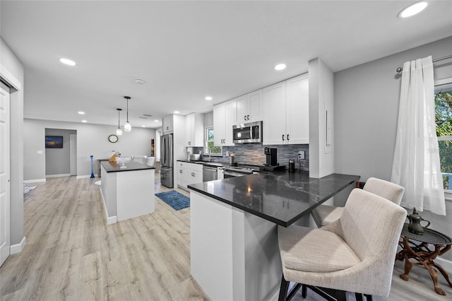 691 Gulf Bay Rd, Longboat Key, FL 34228 - kitchen with stainless steel appliances, recessed lighting, backsplash, white cabinets, and light wood-style flooring