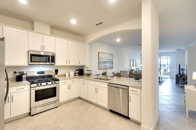 kitchen with appliances with stainless steel finishes, visible vents, a sink, and light stone counters