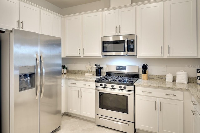 kitchen featuring stainless steel appliances, white cabinets, light stone counters, and light tile patterned floors