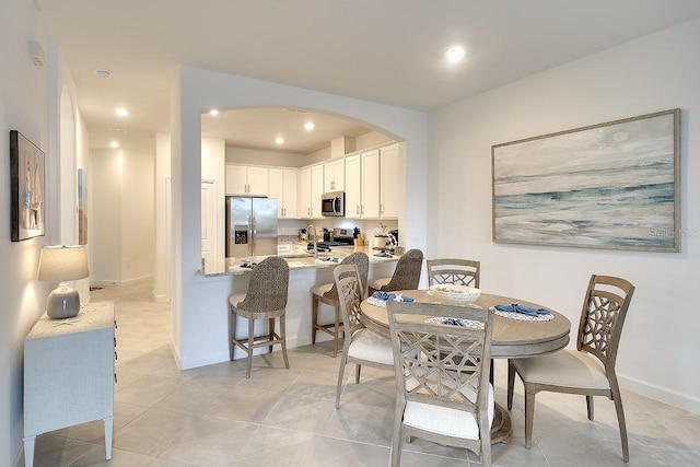 dining area with recessed lighting, baseboards, arched walkways, and light tile patterned flooring