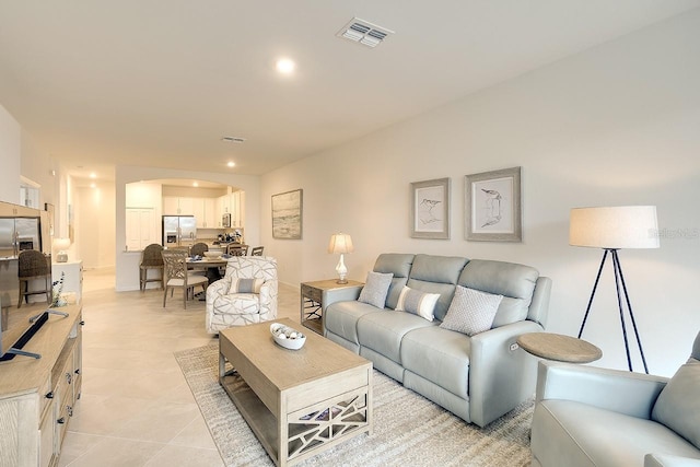 living area with light tile patterned floors, visible vents, arched walkways, and recessed lighting