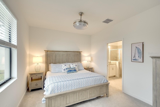 bedroom featuring ensuite bath, baseboards, visible vents, and light colored carpet