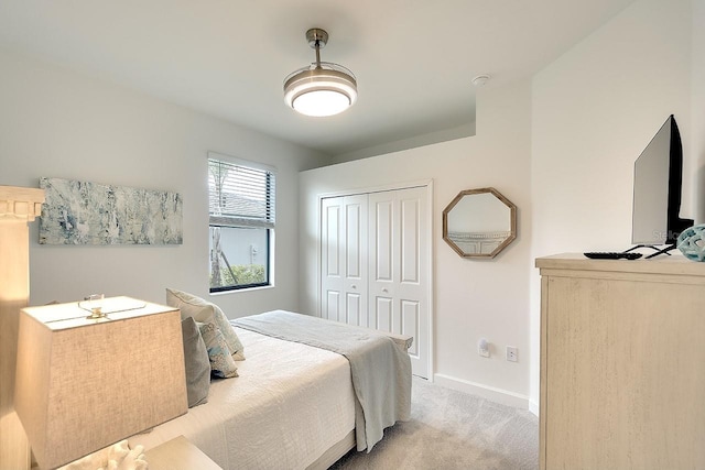 bedroom with a closet, light colored carpet, and baseboards