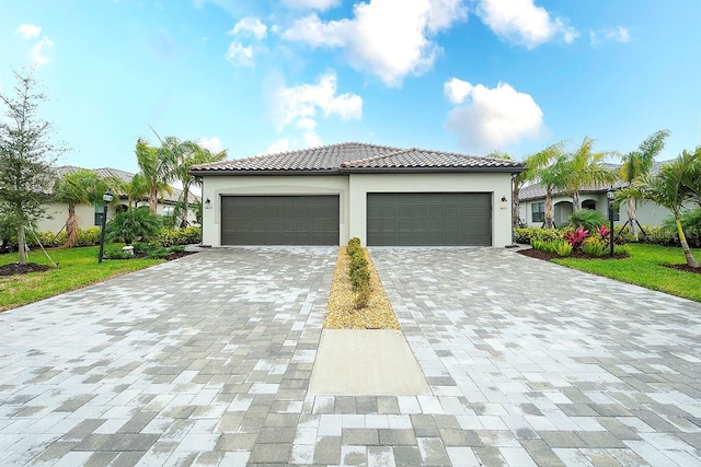 view of front of house with an attached garage, a front yard, decorative driveway, and stucco siding