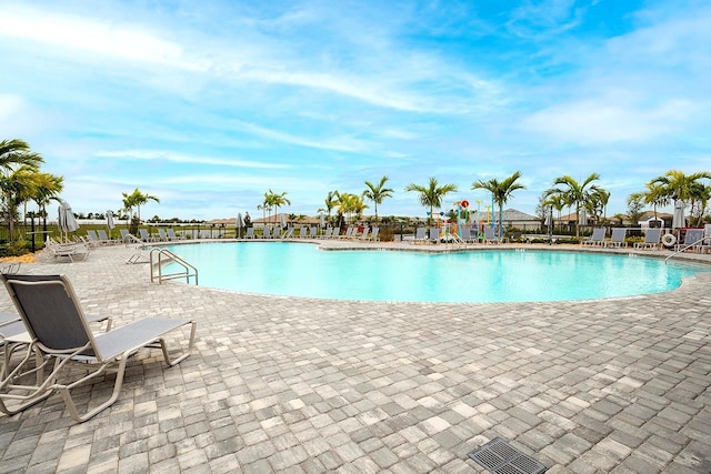 community pool with a patio area and fence