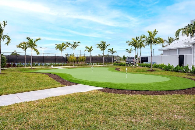 view of community with view of golf course, a lawn, and fence