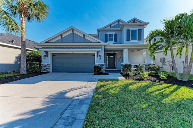 5709 Sunflower Cir, Sarasota, FL 34238 - view of front of property with concrete driveway, board and batten siding, a garage, stone siding, and a front lawn