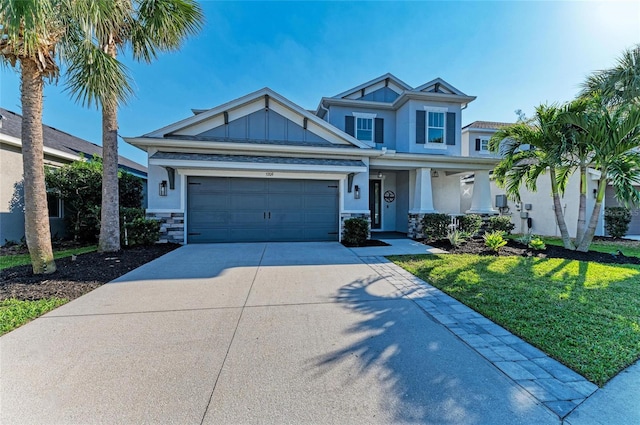 5709 Sunflower Cir, Sarasota, FL 34238 - craftsman-style home featuring concrete driveway, board and batten siding, a garage, stone siding, and a front lawn
