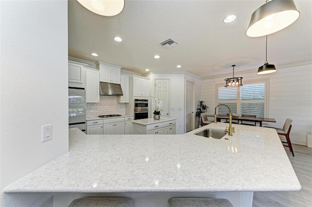 5709 Sunflower Cir, Sarasota, FL 34238 - kitchen with light wood-style flooring, a kitchen breakfast bar, a center island, under cabinet range hood, and a sink