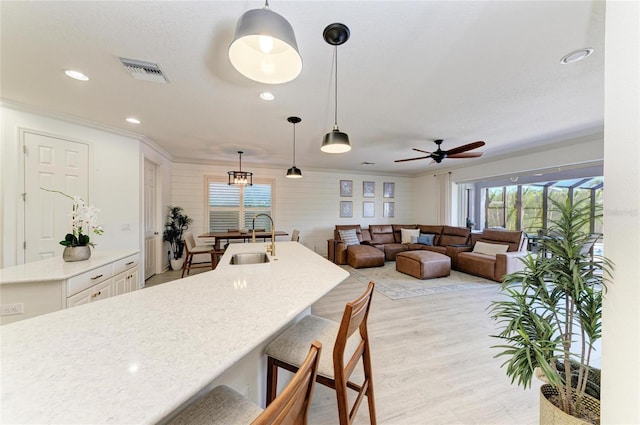 5709 Sunflower Cir, Sarasota, FL 34238 - kitchen with a breakfast bar, light countertops, visible vents, a sink, and an island with sink
