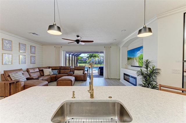 5709 Sunflower Cir, Sarasota, FL 34238 - kitchen featuring visible vents, ornamental molding, a glass covered fireplace, a sink, and wood finished floors