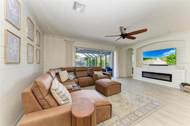 5709 Sunflower Cir, Sarasota, FL 34238 - living room featuring visible vents, a glass covered fireplace, ceiling fan, ornamental molding, and wood finished floors