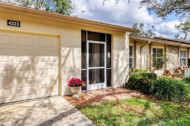 property entrance with a garage and stucco siding