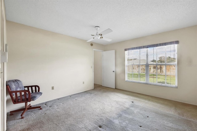 interior space with a textured ceiling, carpet floors, and ceiling fan