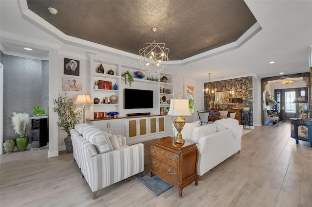 living room featuring a tray ceiling, wine cooler, an inviting chandelier, ornamental molding, and light wood-type flooring