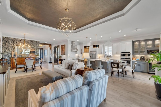 living area featuring crown molding, a tray ceiling, and an inviting chandelier