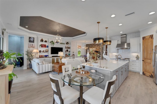 dining area with visible vents, a tray ceiling, crown molding, light wood-style floors, and a chandelier