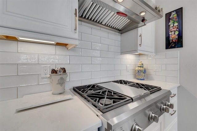 kitchen with white cabinets, stove, light countertops, backsplash, and exhaust hood