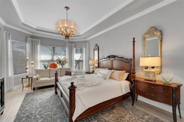 bedroom with crown molding, a tray ceiling, a notable chandelier, and baseboards