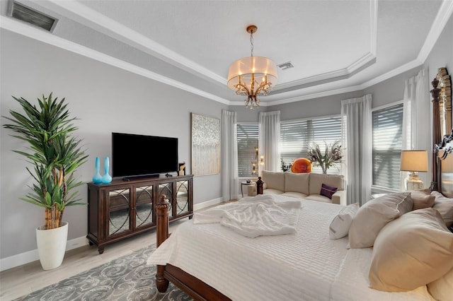 bedroom with a chandelier, light wood-style flooring, a raised ceiling, and visible vents