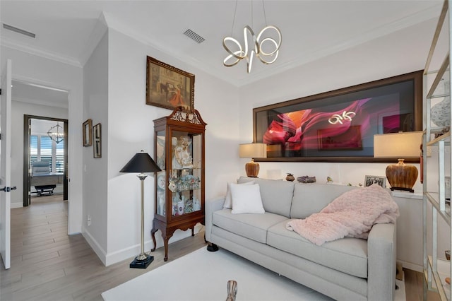 living area with an inviting chandelier, visible vents, wood finished floors, and ornamental molding