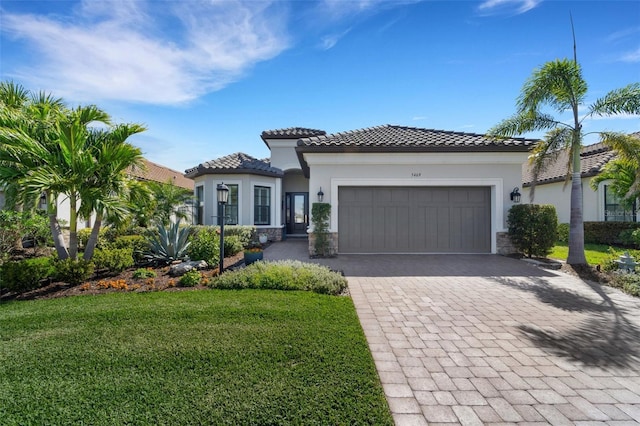 mediterranean / spanish house with a garage, a tile roof, decorative driveway, a front yard, and stucco siding