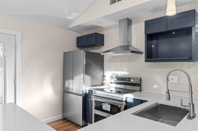 kitchen featuring stainless steel appliances, tasteful backsplash, vaulted ceiling, a sink, and wall chimney exhaust hood