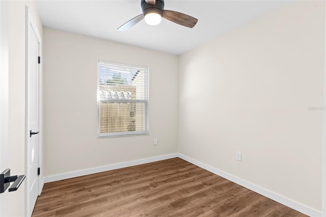 spare room with wood finished floors, a ceiling fan, and baseboards