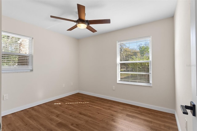 unfurnished room featuring a ceiling fan, plenty of natural light, baseboards, and wood finished floors