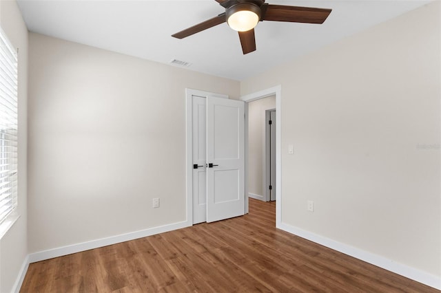 unfurnished bedroom featuring a closet, wood finished floors, visible vents, and baseboards