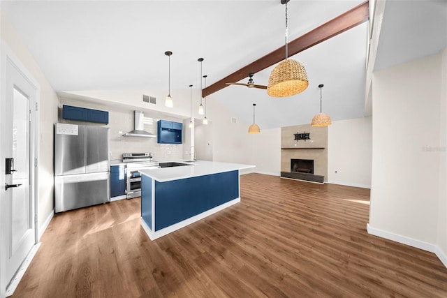 kitchen with blue cabinetry, visible vents, a fireplace with raised hearth, appliances with stainless steel finishes, and wall chimney exhaust hood