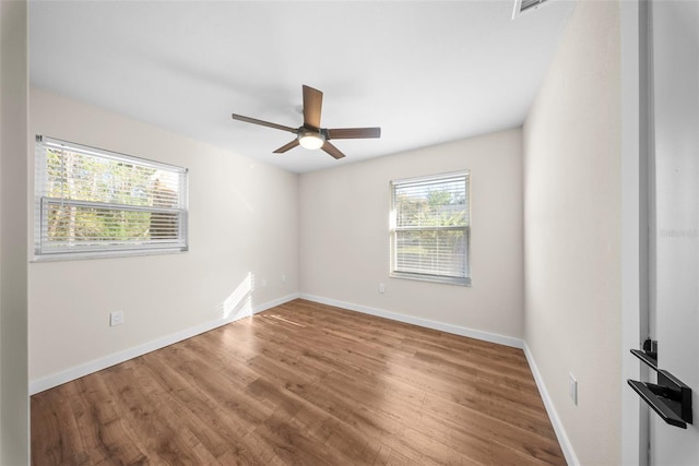 spare room featuring ceiling fan, baseboards, and wood finished floors