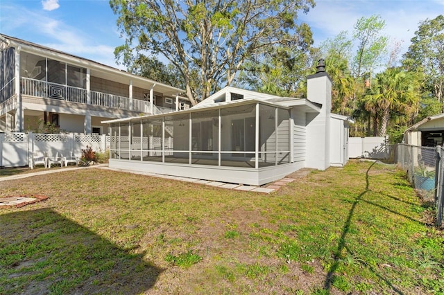 rear view of property featuring a sunroom, a fenced backyard, a chimney, and a lawn