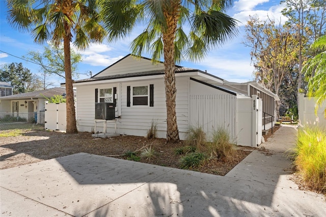 view of side of home with a gate, fence, and cooling unit