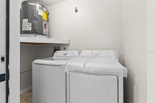 laundry room with washing machine and clothes dryer, water heater, a textured ceiling, wood finished floors, and laundry area