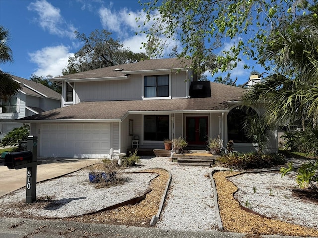 traditional-style house with a garage, concrete driveway, and french doors