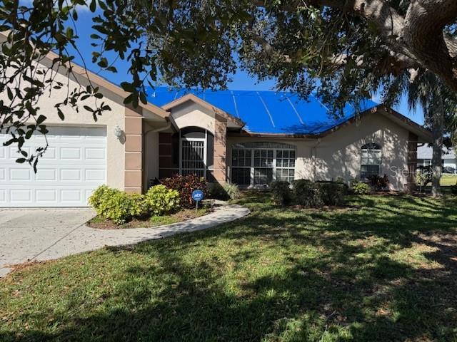 single story home featuring an attached garage, a front lawn, concrete driveway, and stucco siding