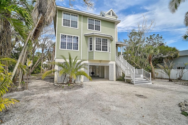 view of front of home with a carport, dirt driveway, and stairs