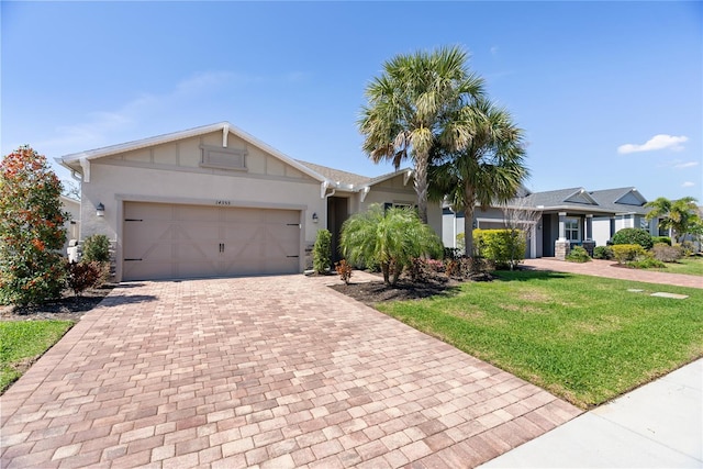 single story home with a front lawn, decorative driveway, an attached garage, and stucco siding