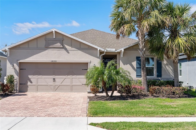 single story home featuring a garage, roof with shingles, decorative driveway, and stucco siding