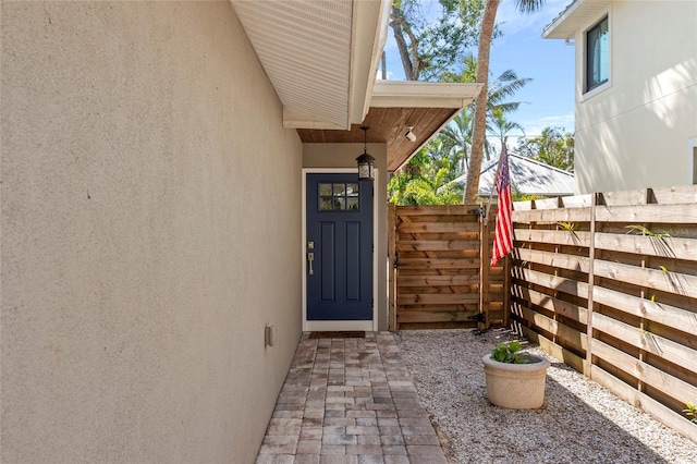 doorway to property featuring fence and stucco siding