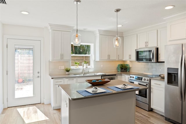 kitchen featuring decorative backsplash, stainless steel appliances, light wood-type flooring, white cabinetry, and a sink