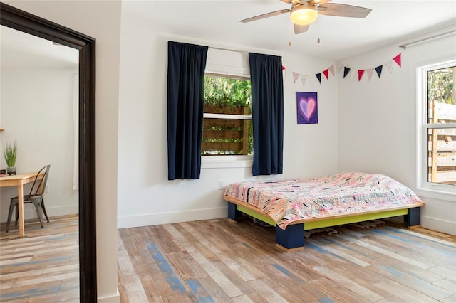 bedroom with a ceiling fan, light wood-style flooring, and baseboards