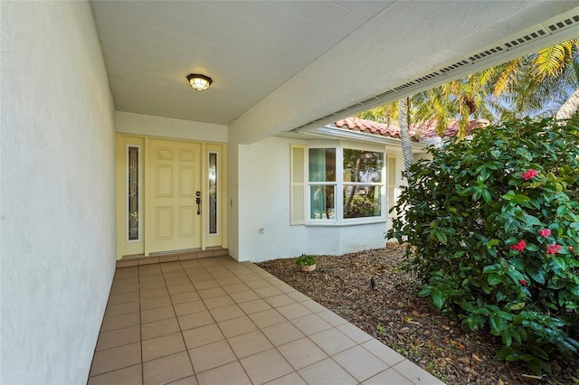 entrance to property featuring a tile roof and stucco siding