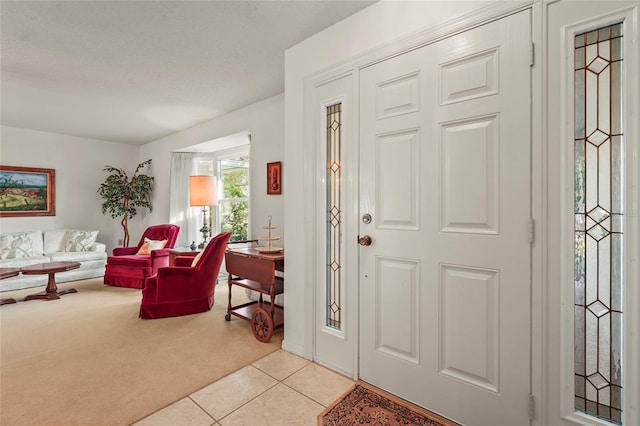 entryway with light tile patterned floors and light carpet