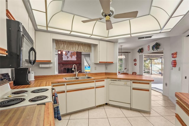 kitchen with light tile patterned floors, white appliances, a sink, visible vents, and wooden counters