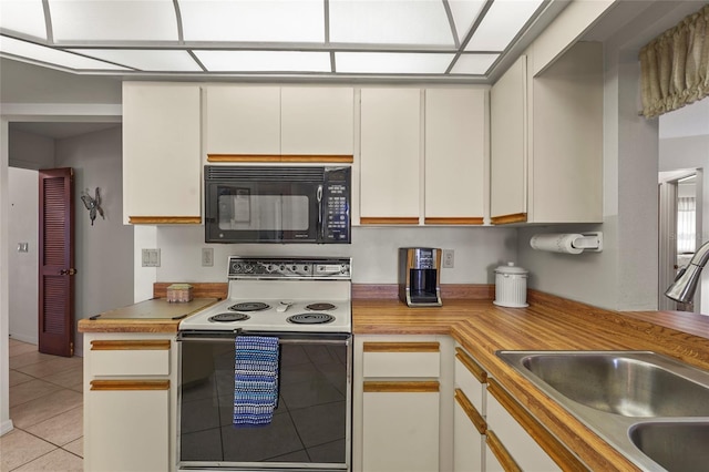 kitchen with black microwave, light tile patterned floors, a sink, light countertops, and electric range oven