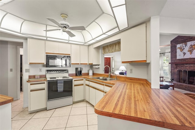 kitchen with black microwave, light tile patterned floors, range with electric stovetop, a sink, and a brick fireplace